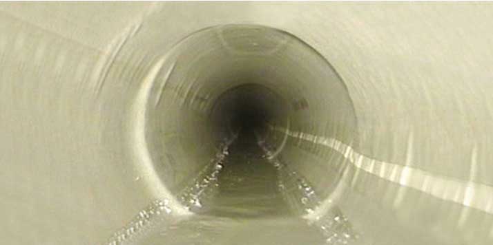 Smooth cream-coloured bore of a cured-in-place liner installed inside an existing drain, with clear flow in the invert