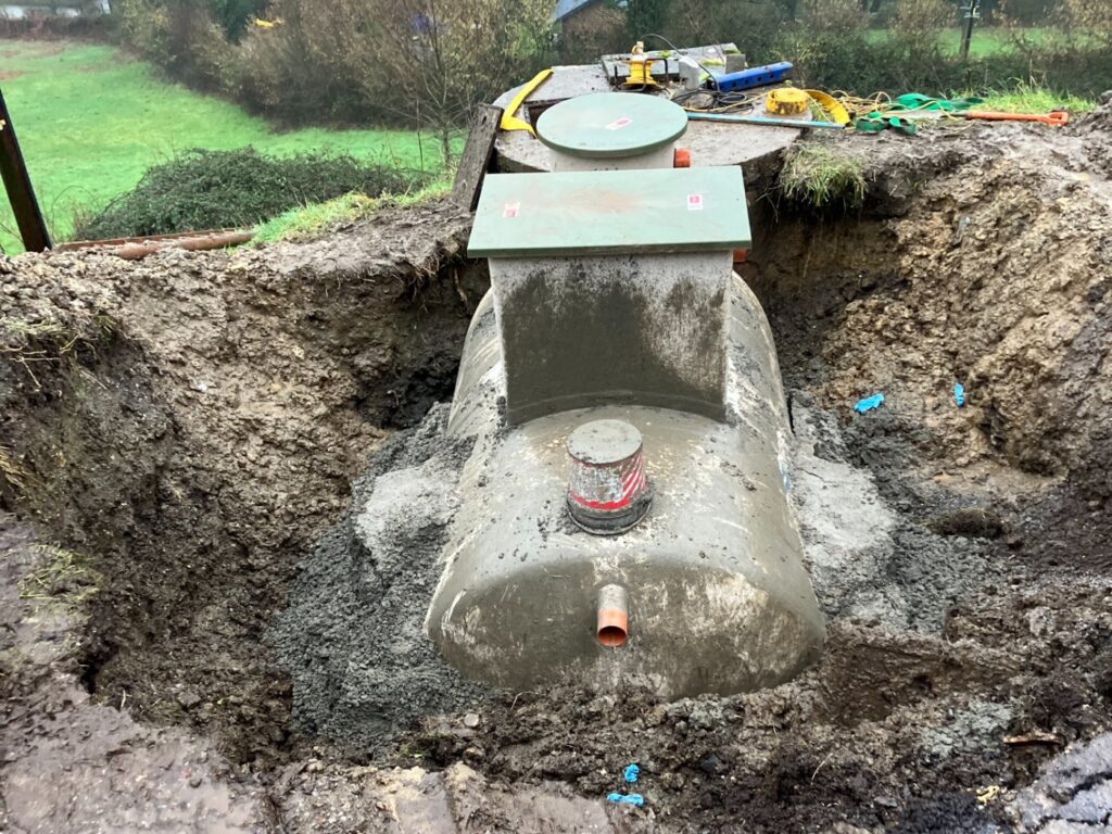 A septic tank set into an excavation in a garden, concrete surround being placed around the base